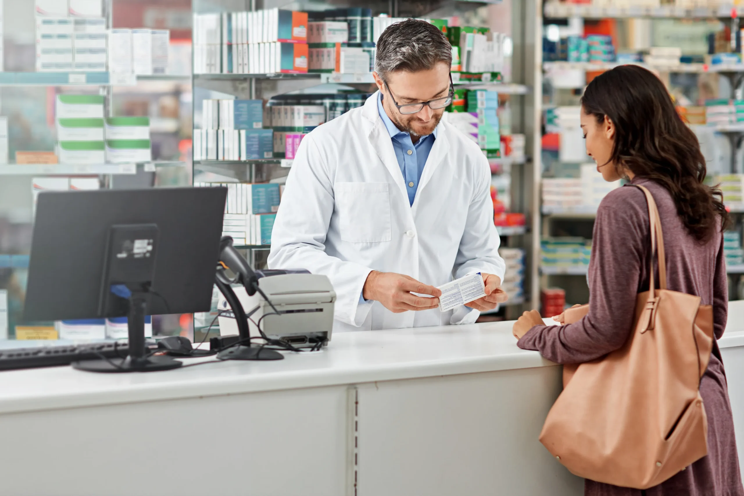 Pharmacist checking prescription information on a counter system integrated with a CRM for Healthcare.