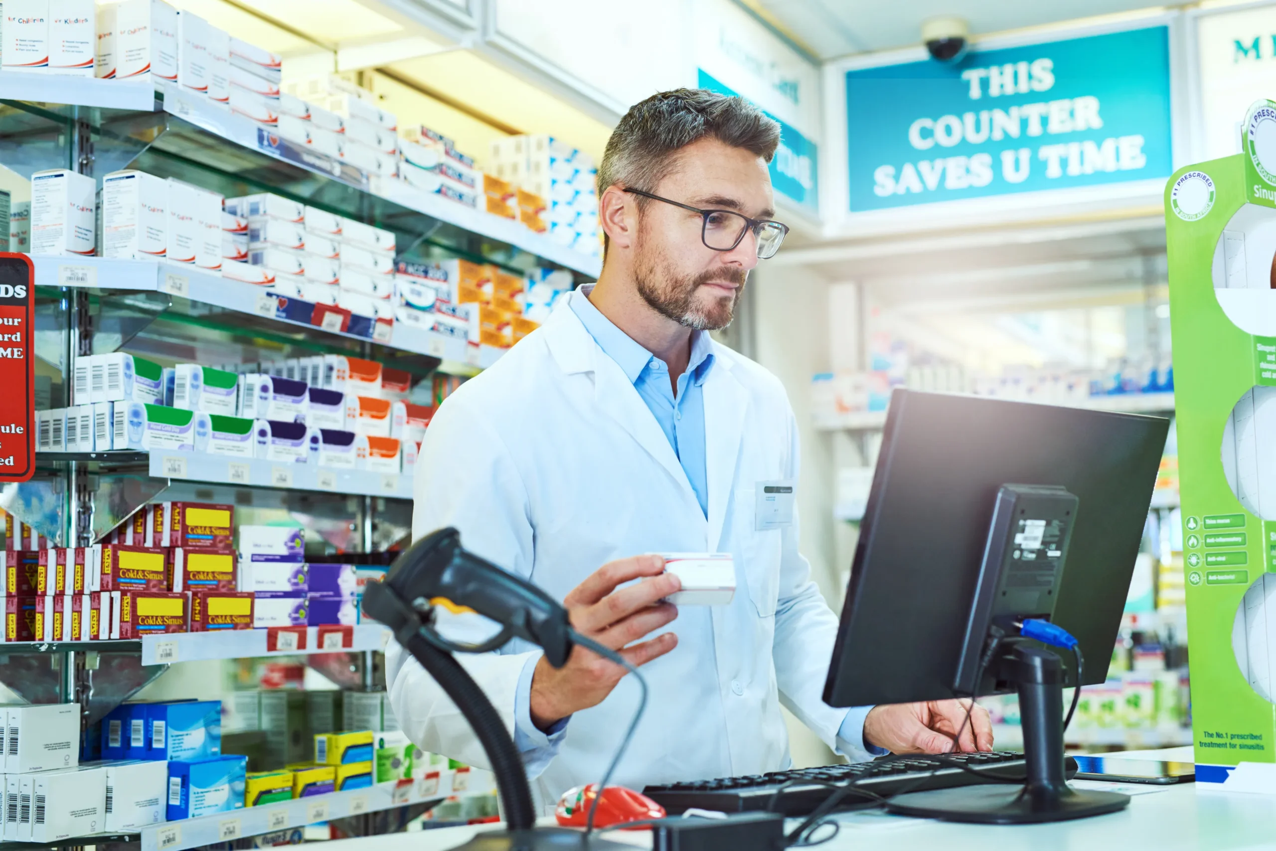 Pharmacist operating desktop terminal to process patient orders and monitor overall healthcare software cost.