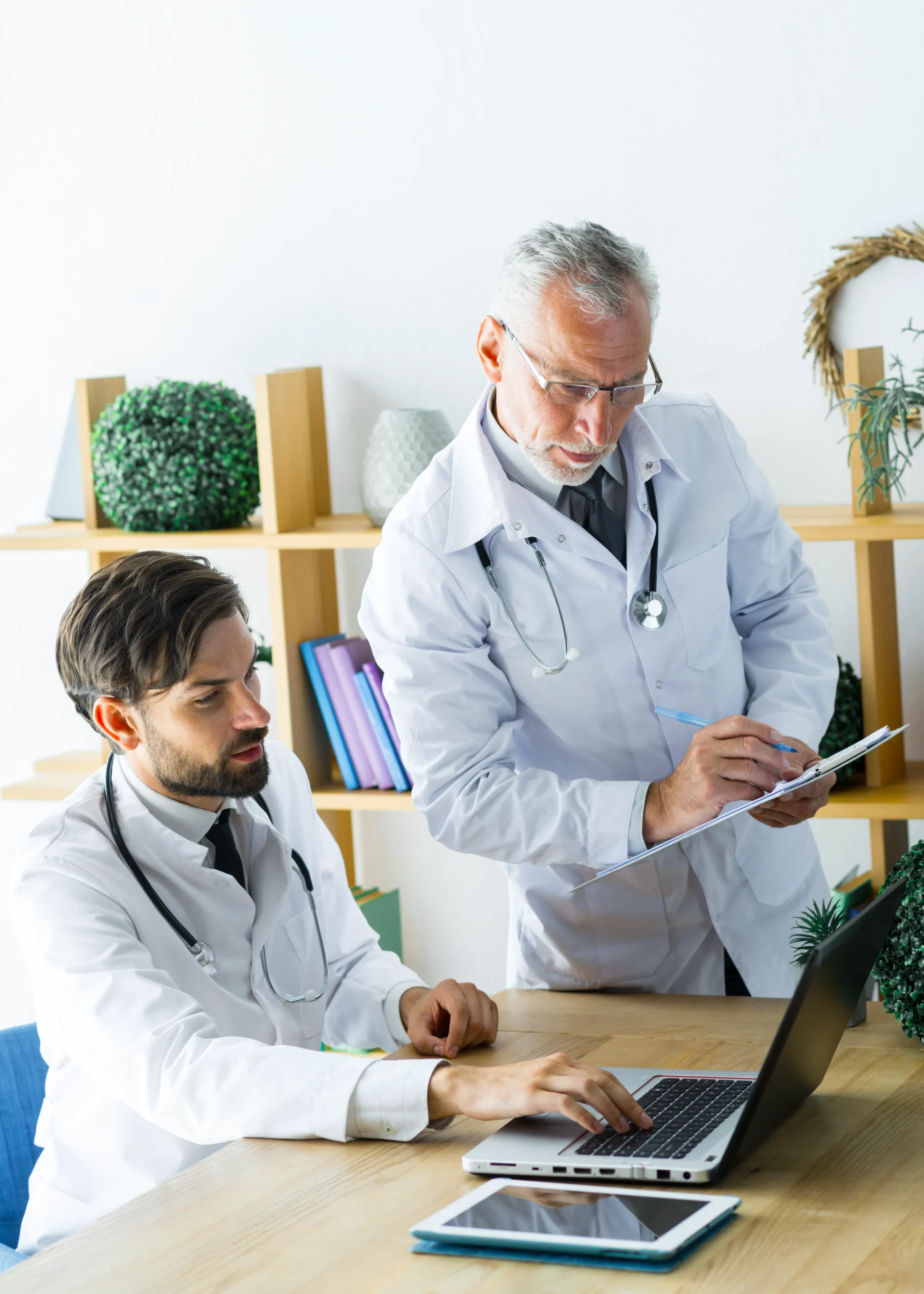 Doctors collaborating at a desk using laptop systems to streamline tasks with healthcare workflow automation.