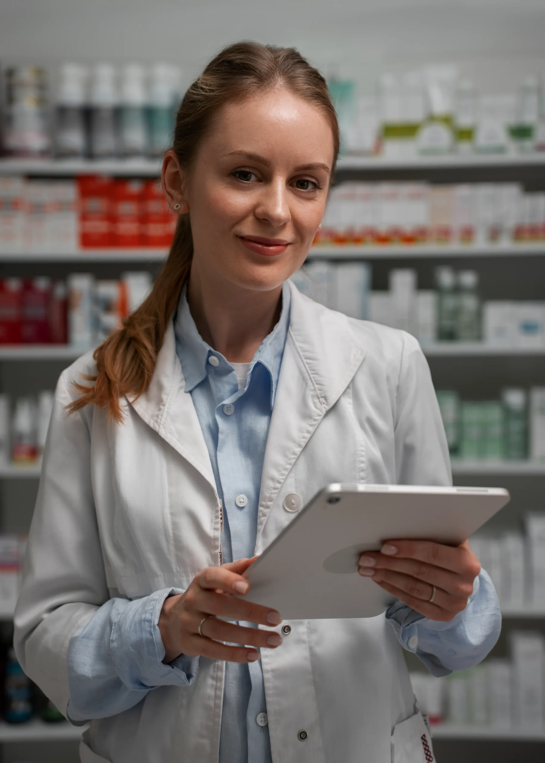 Female pharmacist holding a digital tablet displaying patient records using a Healthcare CRM system.