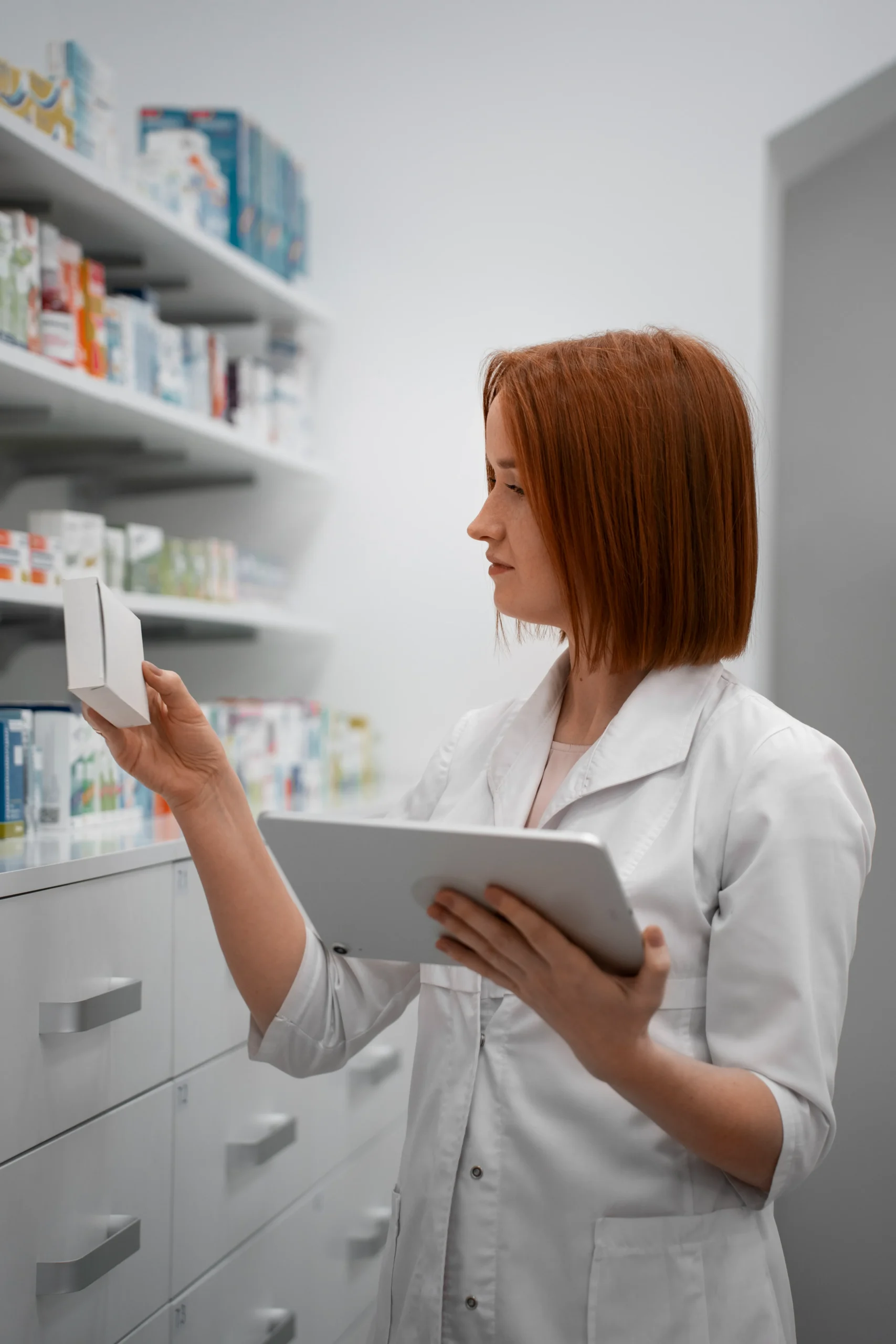 Pharmacist checking inventory against healthcare CRM pricing and management features on a tablet.