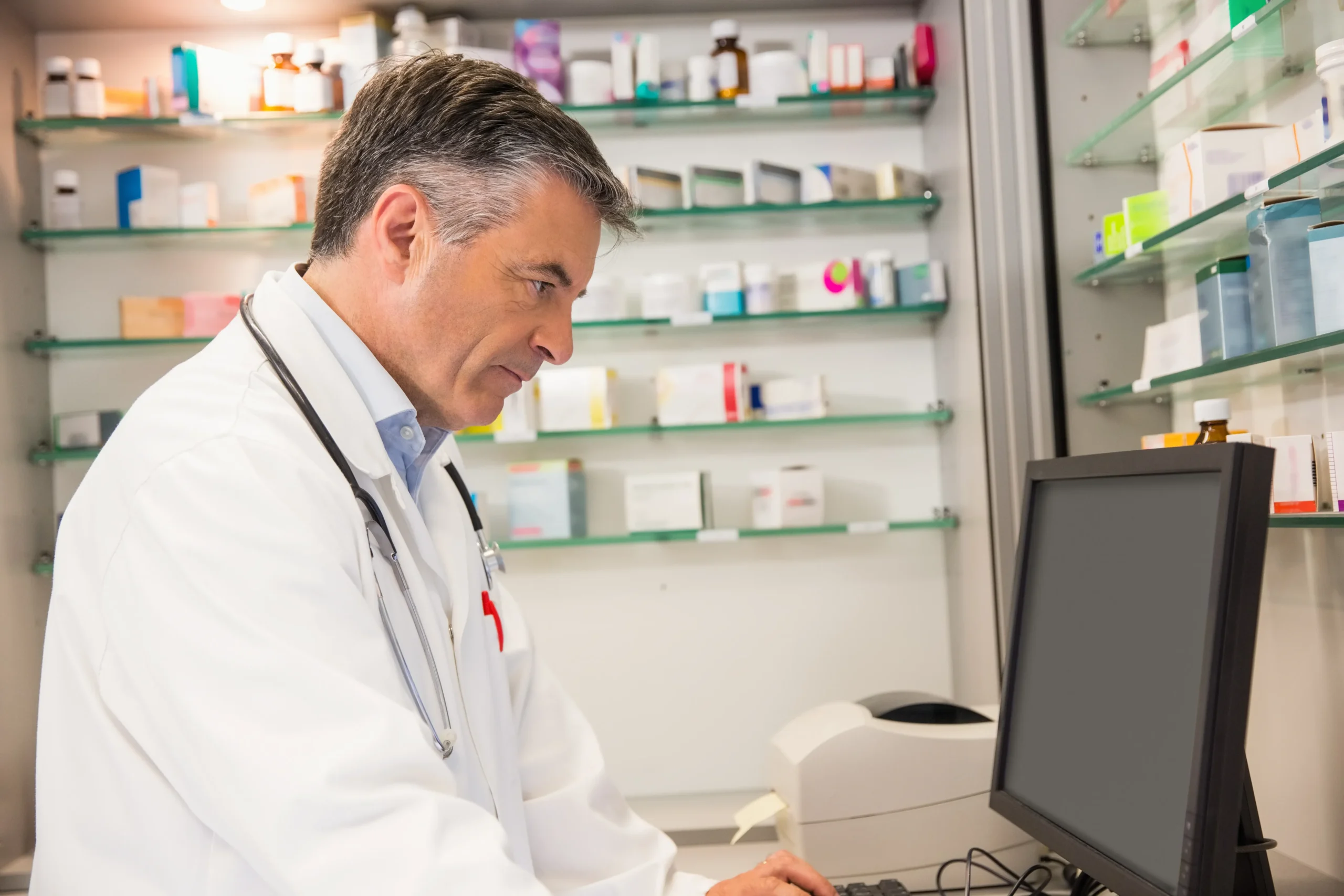 Pharmacist checking automated prescription refill reminders to support patient medication adherence.