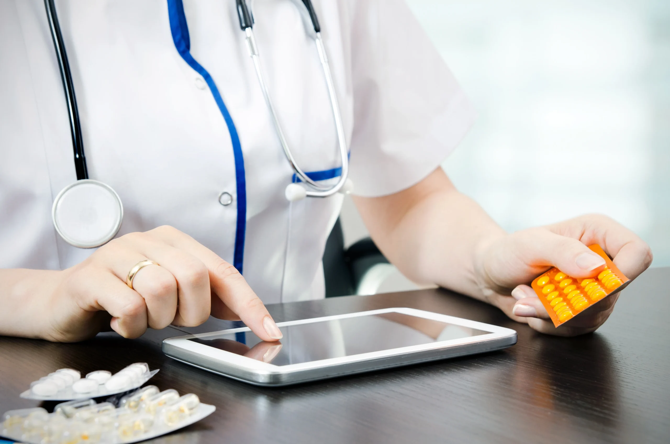 Medical practitioner updating fulfillment status and pharmacy delivery tracking information on a digital tablet.