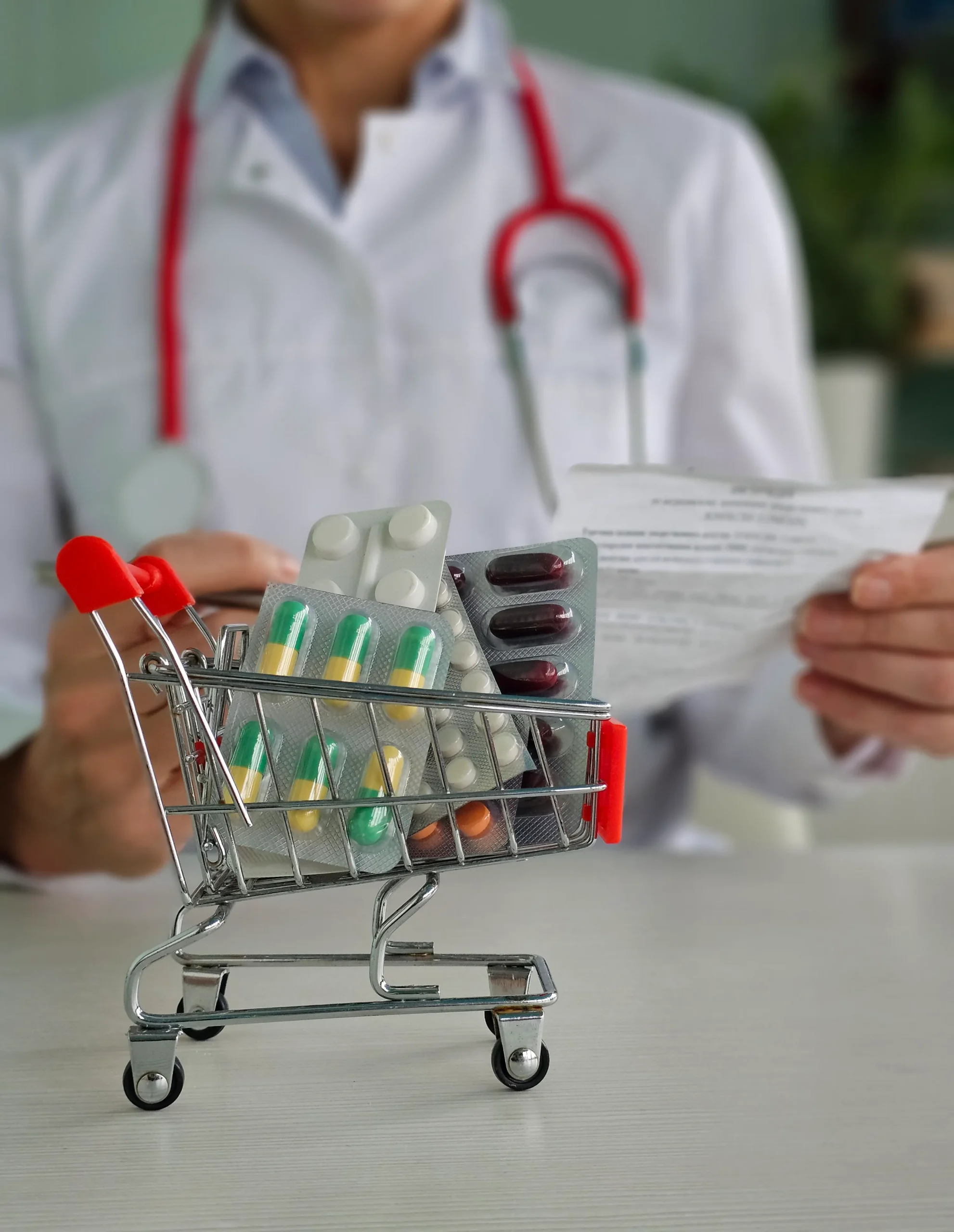 Miniature shopping cart holding medication blister packs managed via a prescription shipment management system.
